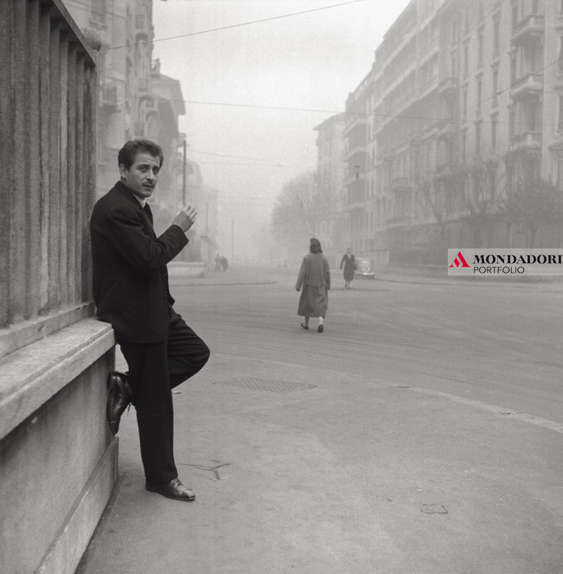 Domenico Modugno fuma una sigaretta, appoggiato contro un muro