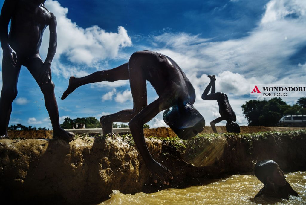 reportage - Alla periferia del campo profughi di Kutupalong, i bambini si tuffano in una pozza d'acqua per rinfrescarsi.