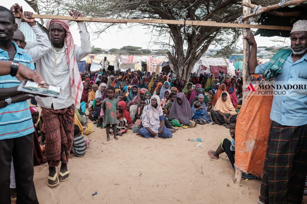 Un gruppo di sfollati aspetta la distribuzione di razioni alimentari in un campo allestito a Mogadiscio per accogliere gli sfollati interni